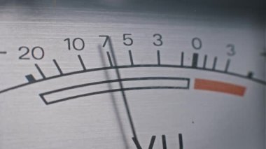 Fırçalanmış metal ölçekte titreşen bir VU metre iğnesinin yakın çekimi ses seviyelerini gösteriyor. Müzik, ses veya teknoloji projeleri için ideal.
