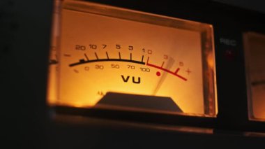 Ilık tonlara ve nostaljik estetiğe vurgu yapan parıldayan bir VU sayacının detaylı yakın çekimi. Retro, teknik veya müzikle ilgili konular için mükemmel bir uyum..