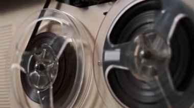 Eski bir makaradan makaraya kayıt cihazının yakın çekim görüntüsü. Makara dönüyor, manyetik bandı gösteriyor. Geçmişe dönük, nostaljik ya da klasik medya projeleri için mükemmel.