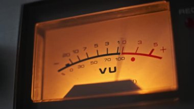 Ses seviyelerini dinamik olarak gösteren analog bir VU ölçer yakın plan, ses mühendisliği ve müzik üretimi kavramlarını göstermek için mükemmel.