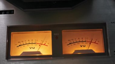 Retro analog ses cihazı üzerinde parlayan kehribar VU metrelere yakın çekim, ses mühendisliği, nostalji veya profesyonel stüdyo ayarları içeren temalar için mükemmel. Klasik ses ekipmanının özü.
