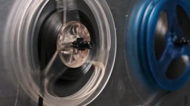 Dönen eski bir makaradan makaraya kayıt cihazının detaylı yakın çekim görüntüsü. Nostalji, teknoloji veya ses üretimi temaları için ideal karmaşık mekanizmaları ve retro estetiği yakalar