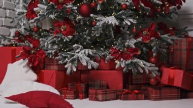 Hediyeler ve yastıklarla çevrili kırmızı kurdeleler ve toplarla süslenmiş bir Noel ağacı samimi bir tatil ortamı yaratır. Mevsimlik videolar için ideal.