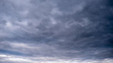 Kümülüs bulutlarıyla dolu bulutlu bir gökyüzü dengesiz ve atmosferik bir zemin oluşturur. Zaman ayarlı. Mavi gökyüzünün ipuçları ara sıra bulutları delip geçerek, sahneye derinlik katıyor.