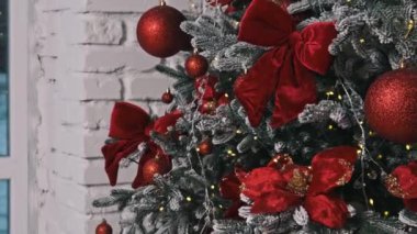 Güzel dekore edilmiş bir Noel ağacı, kırmızı süslemeler, yaylar ve noktalı tüfekler, beyaz tuğladan bir arka plana dizilmiş. Mevsimlik kampanyalar için ideal..