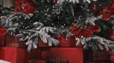 Işıldayan kırmızı süsler ve bereketli noktalarla süslenmiş buzlu bir Noel ağacı dalının detaylı bir görüntüsü. Karmaşık detaylar bayram ruhunu ve mevsimsel güzelliği vurguluyor..