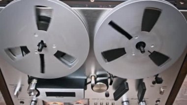 Klasik bir teypte dönen makaraların detaylı bir görüntüsü kusursuz mühendislik ve analog sesin güzelliğini sergiliyor. Nostalji, teknoloji ve müzik yapım tarihi için mükemmel bir tema..