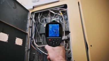 Termal kamera, açık bir dağıtım kutusundaki elektrik kablolarını izliyor. Sıcaklık ölçümleri, rutin elektrik güvenlik kontrolü sırasında tel bağlantıları gösteriyor.