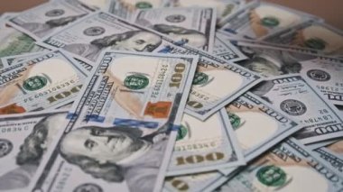 Yüz dolarlık banknotların yığının üzerine düşmesi bolluk ve zenginliğin görsel bir tasvirini oluşturur. Finansman ve yatırımla ilgili içerik için ideal.