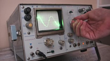 Retro osiloskop, yeşil dalga formu olarak gösterilen bir veri akışının, düğme ve kalibrasyon ayrıntıları elektronik olarak gösterilirken, ekranda nasıl ayarlandığını gösterir.