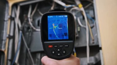 Termal görüntüleyici, ısı artışı ve devre arızaları için kablo ve bağlantıların ısı ölçümlerini gösteren açık elektrik kutusunu inceler. Güvenlik veya binayla ilgili konular için mükemmel.