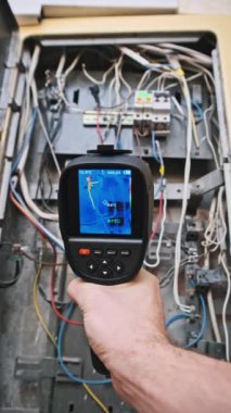 Termal görüntüleyici ile taranan açık bir elektrik panelinin yakın plan görüntüsü, dikey görüntü kablosundaki ısı ve elektrik hatasını saptamak için.