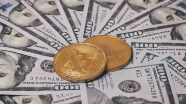 Altın Bitcoin ve Ethereum sikkeleri, mali, kripto para birimi veya ticaretle ilgili görselleştirmeler için ideal, radyal desenli Amerikan yüz dolarlık banknotların arka planında yer alır..