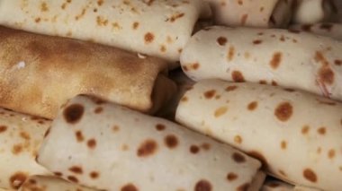 Bir el taze pişmiş, yuvarlanmış bir krep seçiyor, geleneksel Rus lezzetini sergiliyor, mutfak ve kültürel temalar için mükemmel..