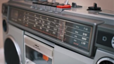 Klasik bir radyo kadranına yakın çekim, frekanslar arasında hareket eden bir iğne. Analog elementlerle birlikte bir retro aygıt üzerindeki ayar ayrıntılandırılıyor.