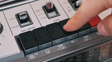 Bir el, düğmeleri ve klasik oyuncunun gümüş gövdesi ile kontrol panelini vurguluyor..
