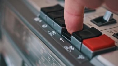 Bir parmak eski moda bir ses oynatıcının çalma tuşuna basar. Müzik çalma işleminin başlatılması üzerinde duruluyor..