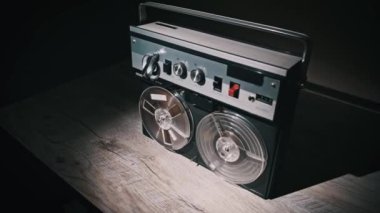 Tahta bir masanın üzerine yerleştirilmiş klasik makaradan makaraya kayıt cihazı çalışıyor. Özgün bir dokunuşa ihtiyaç duyan retro ya da teknolojiyle ilgili görseller için uygun.