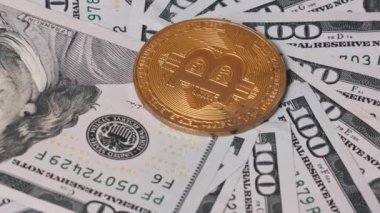 Dijital para ve finansal yatırımı sembolize eden 100 dolarlık banknotlardan oluşan bir yatakta altın bir Bitcoin yatıyor. Finans ve teknoloji projeleri için ideal.