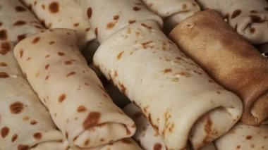 Yakın planda çekilmiş bir el, yeni pişmiş bir krepi toplarken, dokusunu ve sıcaklığını ön plana çıkarıyor..