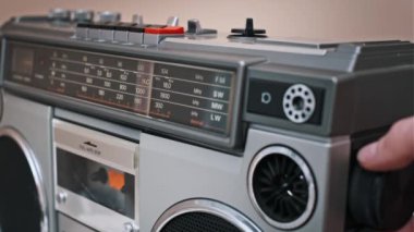 El, eski bir güvertede farklı radyo frekanslarını seçerek akort kadranını ayarlar. Analog radyo mekaniğine gümüş kaplamalı yakın çekim.
