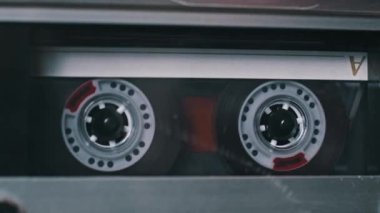 Kırmızı aksanlı şeffaf bir kaset klasik bir destede dönüyor. Klasik ses kaydı sırasında hareket eden makaraların net görünümü, bir retro hissi iletiyor.