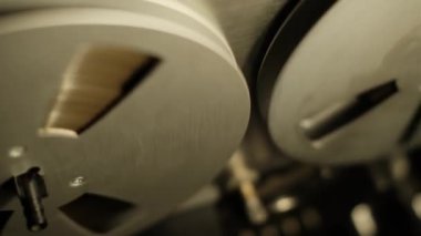 Oynatma sırasında eski bir makaranın dönen makaralarının yakın plan görüntüsü. Mekanik bileşenlerin detaylı çekimi ve bant hareketi, analog kayıtları, nostaljik hissi yakalar..