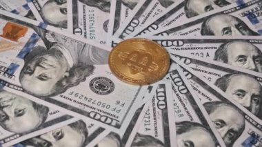 Altın bir Bitcoin 100 dolarlık banknotların dairesel gösteriminin ortasında duruyor..