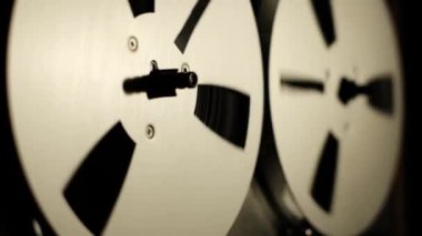 Kapalı çekim video makaralı makara makaralı teyp kayıt cihazını koyu bir arkaplana karşı oynatırken gösteriyor, makaraların pürüzsüz hareketlerini vurguluyor.