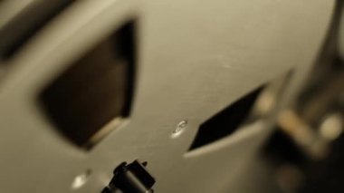 Bir makaradan makaraya son derece yakın çekim kayıt cihazı, makaranın koyu bir arkaplana doğru dönmesi sırasında karmaşık materyal dokularını gösteriyor.