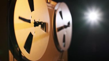 Dönen metal makaralı eski bir makaradan makaraya yakın çekim teybi. Ilık ışıklandırma cihazı koyu bir arkaplan üzerinde vurgular, analog ses çalmanın nostaljik çekiciliğini yakalar.