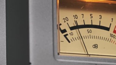 Ses seviyesi ölçeğinde bir iğneyle vintage VU sayacının aşırı yakın çekimi. Sıcak aydınlatma analog estetiğini geliştirir, ses mühendisliği, müzik üretimi ve klasik teknoloji temaları için mükemmeldir.