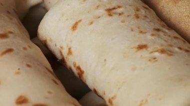 Bu ev yapımı yemeğin sıcaklığını ve dokunaklı dokusunu vurgulayan, altın sarısı bir krep alan bir elin yakından görüntüsü..