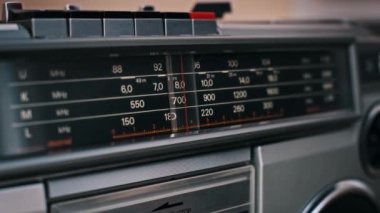 İğne farklı frekanslar arasında sorunsuzca ilerlerken eski bir telsizin yakın çekim görüntüsü. Bir vintage aygıtının analog ayar sürecini gösterir.
