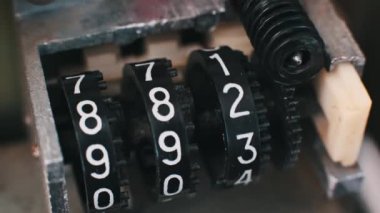 Tekerlekler döndükçe parmakları değişen analog mekanik sayacın yakın görüntüsü. Vintage sayma cihazlarının karmaşık mekaniklerini ve güzelliğini gösterir.