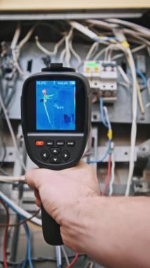 Termal görüntülemeli dikey bir görüntü sistem kontrolü sırasında açık bir elektrik kutusundaki sıcak noktaları ortaya çıkarır. Teknik denetimler ve altyapı hakkında içerik için ideal.