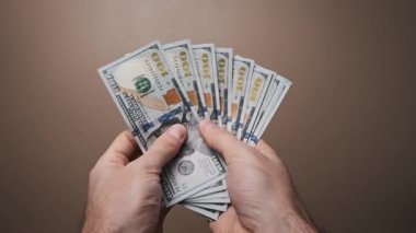 Yakın plan çekimde, yönetim, finans ve ekonomiyi sembolize eden 100 dolarlık banknotların dikkatle ele alındığı görülüyor..