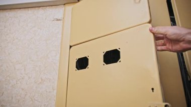 Eski, krem renkli bir metal bağlantı kutusunun kapısı çok renkli iç kablolar ve teknik bakım için bağlantı noktaları ortaya çıkarmak için açılır.