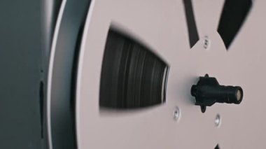 Eski bir ses oynatıcının iki makarasının yakın çekimi. Makara dönüyor, kasetin hareket ettiğini gösteriyor, retro teknolojiyi ve analog kayıt sürecini vurguluyor.