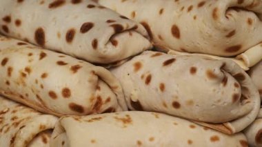 Rus blini olarak bilinen iştah açıcı doldurulmuş gözlemelerin yakın çekimi altın-kahverengi dokularını ve lezzetli dolgusunu sergiliyor..