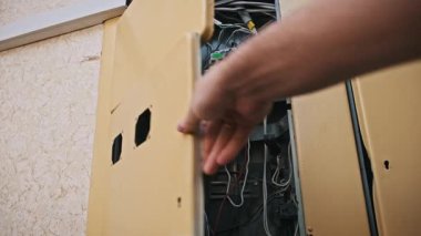 Açık elektrik paneli kutusunun içindeki el hareketleri noktalarını kapat. Karmaşık kablolar, karışık kablolar ve yüklenmiş kırıcı bileşenler, karmaşık tasarımı gösteriyor..