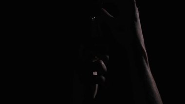 Klasik bir Edison ampulünü vidalayan ellerin yakın çekimi. Sıcak ışık, elleri ve yakın bölgeyi aydınlatarak karanlık arka planda bir kontrastı oluşturur. Harekete ve ampullere odaklan..