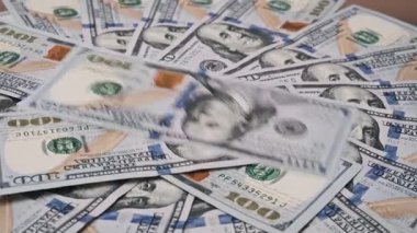 Yakın plan çekimde, dağınık ve katmanlı 100 dolarlık banknotlar ortaya çıkıyor. Benjamin Franklin 'in detaylı portresi çerçeveye kavramsal bir bakış açısıyla hakim..