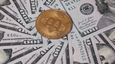 Altın bir Bitcoin, dairesel düzenlenmiş 100 dolarlık banknotların üzerinde yer alır. Mali konular için uygun.