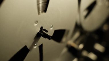 Eskimiş makaralı makaralı makaralı makaraların yakın plan çekimleri koyu arkaplana karşı dönerek çalma sırasında hareketi vurguluyor. Dönen mekanik parçalarla retro estetiği yakalar.