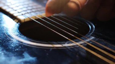 Gitarın telleri, odaklı stüdyo ışıkları altında bir pena kullanılarak koparılıyor. Telleri koparan el gibi vibratörler yaratılıyor. Detaylı çekim..