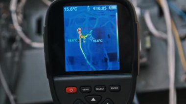 Termal görüntüleyici, açık bir elektrik panelinin içindeki kablolar ve devre kesicilerdeki ısı değişimlerini gösteriyor. Bu çekim elektrik sorununu vurguluyor..