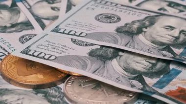 Bitcoin, Ethereum ve Litecoin paralarının yüz dolarlık banknotlardan oluşan bir yatağın üzerinde yakın plan görüntüsü. Daha fazla banknot eklenir, kısmen kripto para birimini kapsar.