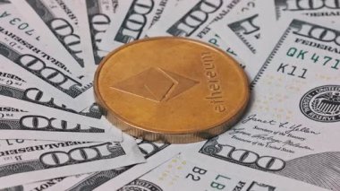 Şifreleme ve fiat para biriminin kesişimini temsil eden 100 dolarlık banknotların olduğu bir yelpazede altın bir Ethereum madeni para sergileniyor. Finans ve teknik görseller için harika..