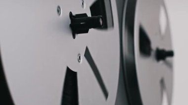 Eski bir makaranın yan görüntüsü bant makaralarının döndüğü, klasik estetiği ve bant kaydının sürekli hareketini vurgulayan eski bir makara..